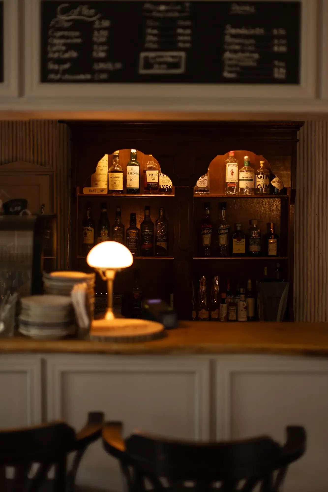 Tresen des Café Kansjerf mit Kreidetafel, Flaschenregal und leuchtender Pilzlampe